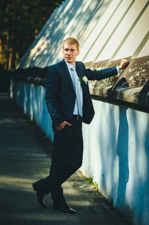 Happy young groom on their wedding day. Handsome groom thinking and putting on his bowtie while getting dressed for his wedding. Handsome caucasian man in tuxedoの写真素材