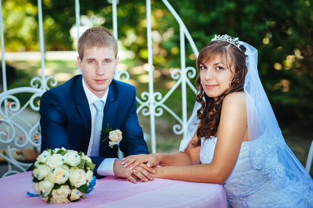 Bride and groom posing at the decorated banquet table in the park in the summer. Enjoy a moment of happiness and love. A series of photos in my portfolio.の写真素材