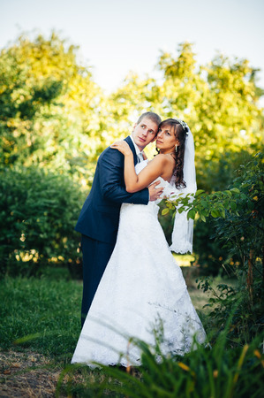 Bride and Groom at wedding Day walking Outdoors on spring nature. Bridal couple, Happy Newlywed woman and man embracing in green park. Loving wedding couple outdoor.の写真素材