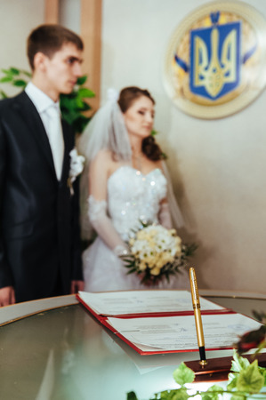 Wedding ceremony. Registry office. A newly-married couple signs the marriage document. Young couple signing wedding documents.の写真素材