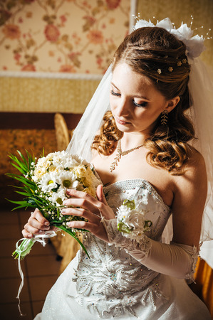 Portrait beautiful bride with bouquet of flowers on luxury interior in wedding day.の写真素材