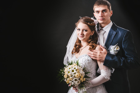Bride and groom kissing and hugging. wedding photo taken in the studio on a black background.の写真素材