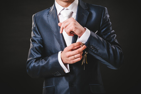 Hands of wedding groom getting ready in suit. black studio background.