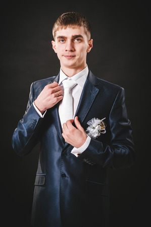 Hands of wedding groom getting ready in suit. black studio background.の写真素材