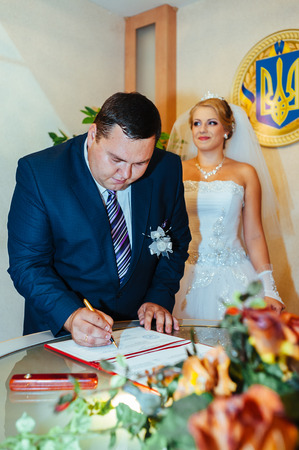 Wedding ceremony. Registry office. A newly-married couple signs the marriage document.Young couple signing wedding documents.の写真素材