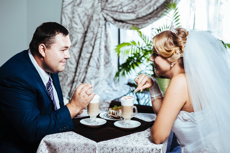 Hands of bride and groom. Cappuccino or latte coffee with heart shape. bride and groom drink a cup of Coffee latte on the date. Happy bride and groom drink a cup of Coffee latte with heart design.の写真素材