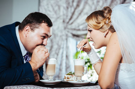 Hands of bride and groom. Cappuccino or latte coffee with heart shape. bride and groom drink a cup of Coffee latte on the date. Happy bride and groom drink a cup of Coffee latte with heart design.の写真素材