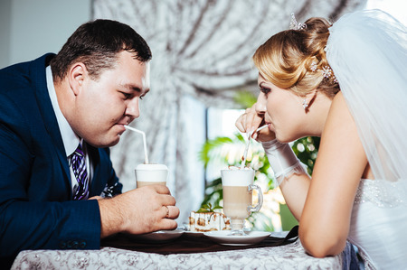 Hands of bride and groom. Cappuccino or latte coffee with heart shape. bride and groom drink a cup of Coffee latte on the date. Happy bride and groom drink a cup of Coffee latte with heart design.の写真素材