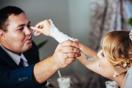 Hands of bride and groom. Cappuccino or latte coffee with heart shape. bride and groom drink a cup of Coffee latte on the date. Happy bride and groom drink a cup of Coffee latte with heart design.の写真素材