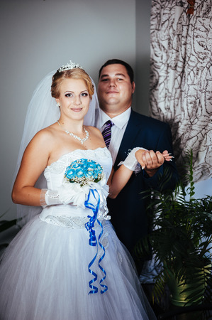 Charming bride and groom on their wedding celebration in a luxurious restaurant. Wedding bouquet of flowers and bridal dress. newly married couple in luxury modern hotel hall.の写真素材