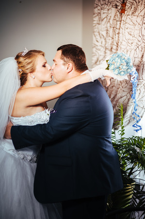 Charming bride and groom on their wedding celebration in a luxurious restaurant. Wedding bouquet of flowers and bridal dress. newly married couple in luxury modern hotel hall.の写真素材