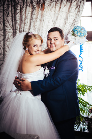 Charming bride and groom on their wedding celebration in a luxurious restaurant. Wedding bouquet of flowers and bridal dress. newly married couple in luxury modern hotel hall.の写真素材