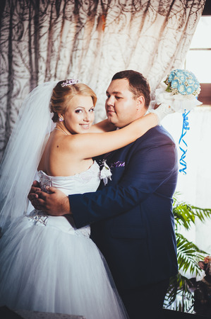 Charming bride and groom on their wedding celebration in a luxurious restaurant. Wedding bouquet of flowers and bridal dress. newly married couple in luxury modern hotel hall.の写真素材