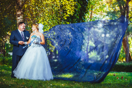 Bride and groom in the park with flying fabricの写真素材