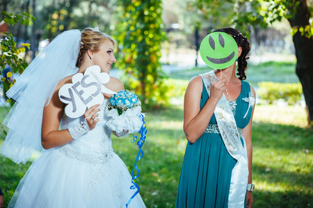 portrait of newlywed couple dancing and having fun with bridesmaids and groomsmen in green sunny park.の写真素材