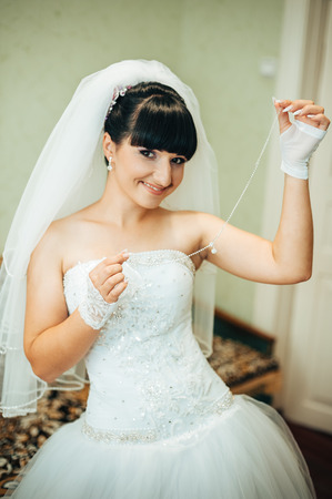 Bride getting ready. beautiful bride in white wedding dress with hairstyle and bright makeup. Happy sexy girl waiting for groom. Romantic lady in bridal dress have final preparation for wedding.の写真素材