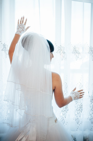 Bride getting ready. beautiful bride in white wedding dress with hairstyle and bright makeup. Happy sexy girl waiting for groom. Romantic lady in bridal dress have final preparation for wedding.の写真素材