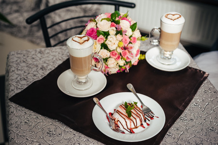 panna cotta and coffee latte with hearts design and wedding bouquet of flowers. Panna Cotta with chocolate and vanilla. frozen yogurt coffee and cacao panna cotta in the cup nuts on the plate.の写真素材