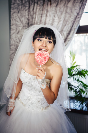 Portrait of a young bride with a heart-shaped candy lollipop.の写真素材