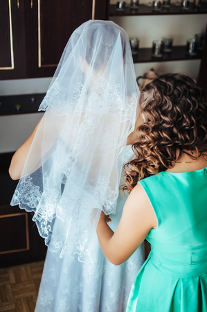 Bride getting ready. beautiful bride in white wedding dress with hairstyle and bright makeup. Happy sexy girl waiting for groom. Romantic lady in bridal dress have final preparation for wedding.の写真素材