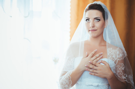 Bride getting ready. beautiful bride in white wedding dress with hairstyle and bright makeup. Happy sexy girl waiting for groom. Romantic lady in bridal dress have final preparation for wedding.の写真素材