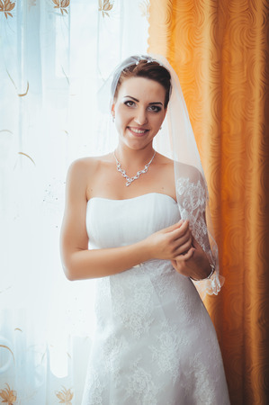 Bride getting ready. beautiful bride in white wedding dress with hairstyle and bright makeup. Happy sexy girl waiting for groom. Romantic lady in bridal dress have final preparation for wedding.の写真素材