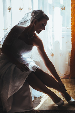 Bride getting ready. beautiful bride in white wedding dress with hairstyle and bright makeup. Happy sexy girl waiting for groom. Romantic lady in bridal dress have final preparation for wedding.の写真素材