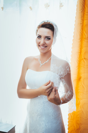 Bride getting ready. beautiful bride in white wedding dress with hairstyle and bright makeup. Happy sexy girl waiting for groom. Romantic lady in bridal dress have final preparation for wedding.の写真素材