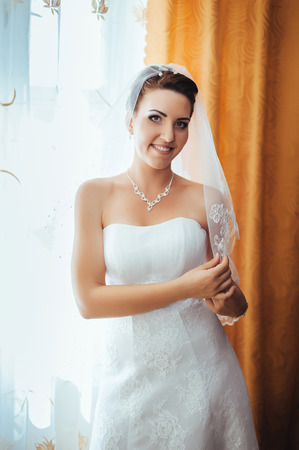 Bride getting ready. beautiful bride in white wedding dress with hairstyle and bright makeup. Happy sexy girl waiting for groom. Romantic lady in bridal dress have final preparation for wedding.の写真素材