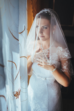 Bride getting ready. beautiful bride in white wedding dress with hairstyle and bright makeup. Happy sexy girl waiting for groom. Romantic lady in bridal dress have final preparation for wedding.の写真素材