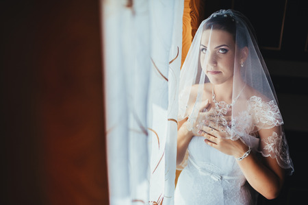 Bride getting ready. beautiful bride in white wedding dress with hairstyle and bright makeup. Happy sexy girl waiting for groom. Romantic lady in bridal dress have final preparation for wedding.の写真素材
