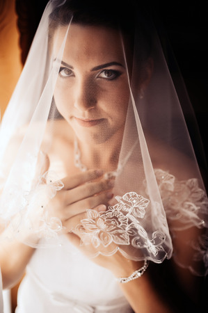 Bride getting ready. beautiful bride in white wedding dress with hairstyle and bright makeup. Happy sexy girl waiting for groom. Romantic lady in bridal dress have final preparation for wedding.の写真素材