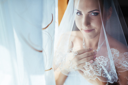 Bride getting ready. beautiful bride in white wedding dress with hairstyle and bright makeup. Happy sexy girl waiting for groom. Romantic lady in bridal dress have final preparation for wedding.の写真素材