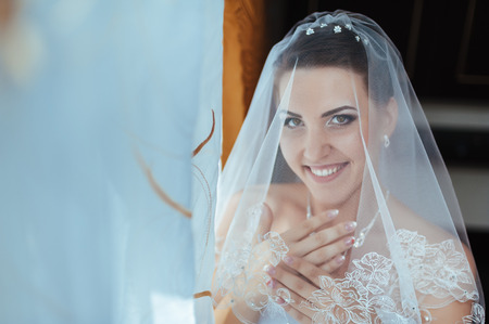 Bride getting ready. beautiful bride in white wedding dress with hairstyle and bright makeup. Happy sexy girl waiting for groom. Romantic lady in bridal dress have final preparation for wedding.の写真素材