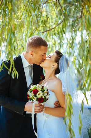 Bride and Groom at wedding Day walking Outdoors on spring nature. Bridal couple, Happy Newlywed woman and man embracing in green park. Loving wedding couple outdoor. Wedding shot of bride and groom in parkの写真素材