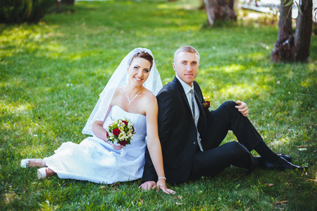 Bride and Groom at wedding Day walking Outdoors on spring nature. Bridal couple, Happy Newlywed woman and man embracing in green park. Loving wedding couple outdoor. Wedding shot of bride and groom in parkの写真素材