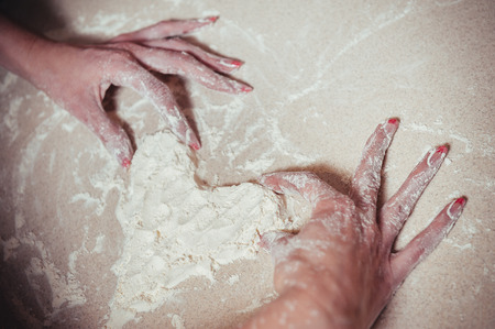 Woman holding dough heart in his hands.の写真素材