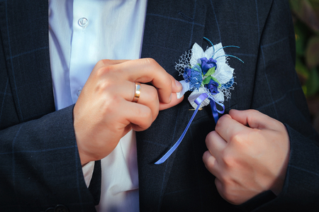 Groom buttoning his jacket in the park.