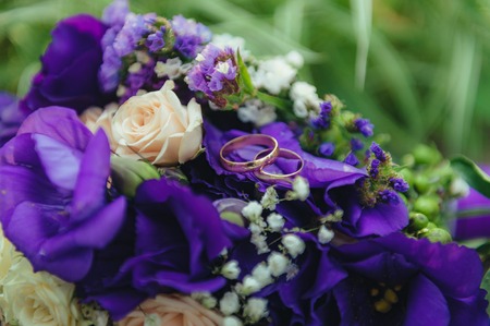 wedding bouquet. golden rings and two glasses of shampagne on the background of green grass and stone.の写真素材