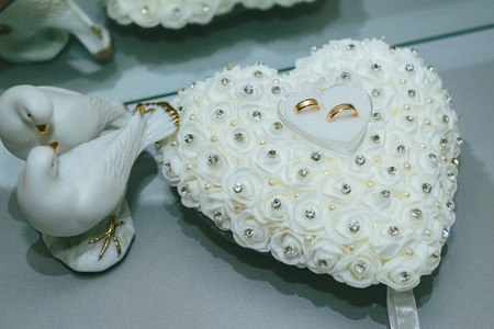 Wedding rings on the white heart pillow.の写真素材