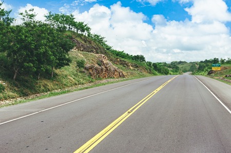 Road crossing the forest with cloudy sky and mountain viewの写真素材