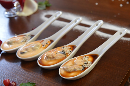 party appetizers. Four white spoons with mussels Spanish Tapas . Extreme close up macro picture. Fresh juicy mussels with red pepper on a white porcelain spoon. Seafood dish. Food photography.の写真素材