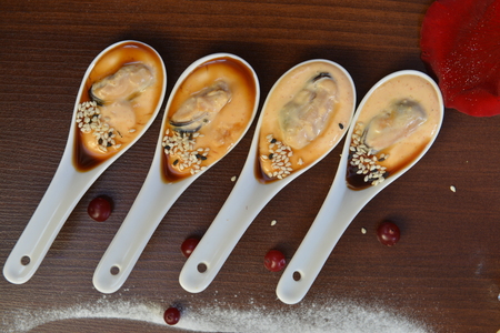 party appetizers. Four white spoons with mussels Spanish Tapas . Extreme close up macro picture. Fresh juicy mussels with red pepper on a white porcelain spoon. Seafood dish. Food photography.の写真素材
