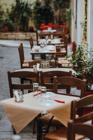 A table with glasses, white tablecloth and napkins in a street caffe. Selective focus.の写真素材