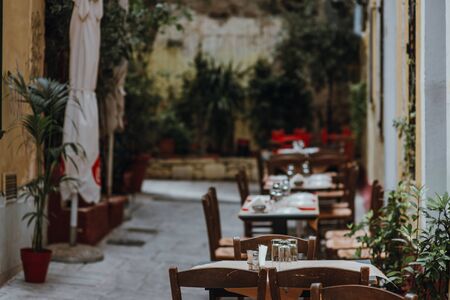A table with glasses, white tablecloth and napkins in a street caffe. Selective focus