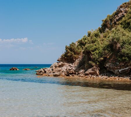 Peaceful beach with golden island and sand at sunset, sea with calm water, Greece