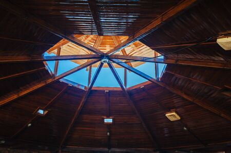 Hole in a roof letting in light and the blue sky.
