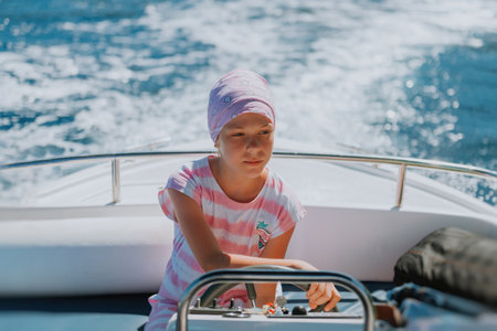 beautiful girl drive the speed boat in Greece. Little girl on a private yacht in the sea. Attractive young girl in posing on a yacht at a sunny summer day.の写真素材