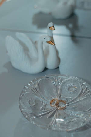 TWO GOLD WEDDING RINGS LIE ON A CRYSTAL SAUCER.の写真素材