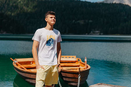 Young man looking at Black Lake, Durmitor National Park, Zabljak, Montenegro. Hipster traveler enjoying view of Black Lakeの写真素材